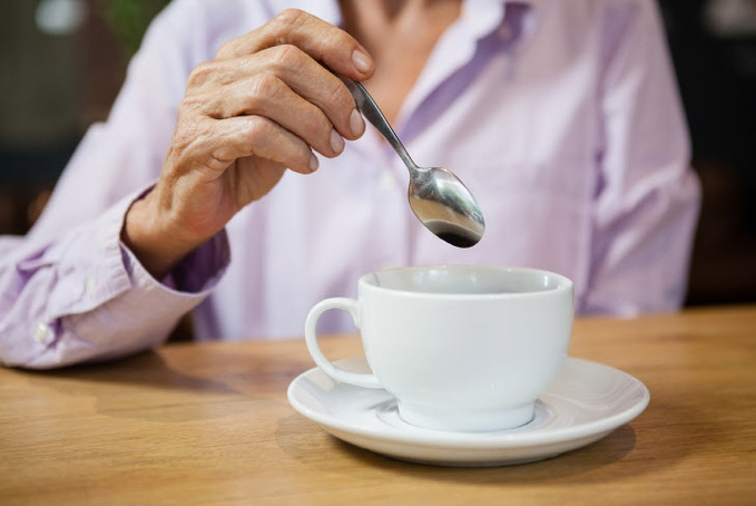 Woman stirring coffee while sitting at table in cafe